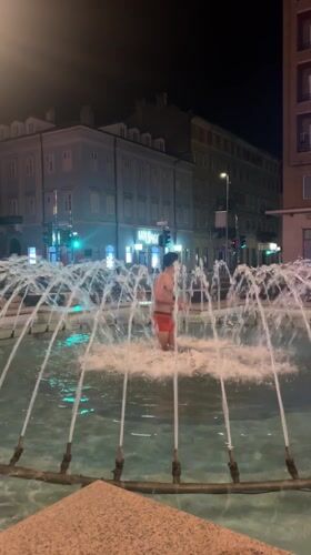 Man in red trunks enters illuminated fountain in Rijeka