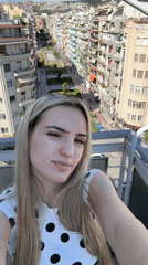 Woman takes selfies on Thessaloniki balcony overlooking city avenue