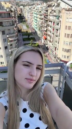 Woman takes selfies on Thessaloniki balcony overlooking city avenue