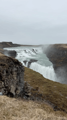 Tourists gather at Iceland's Gullfoss waterfall under cloudy skies