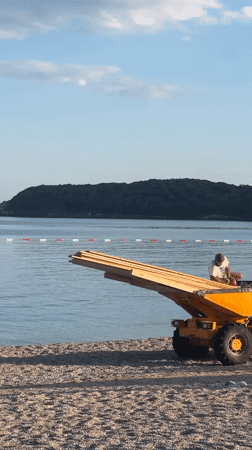 Two men operate yellow vehicle on Montenegro beach
