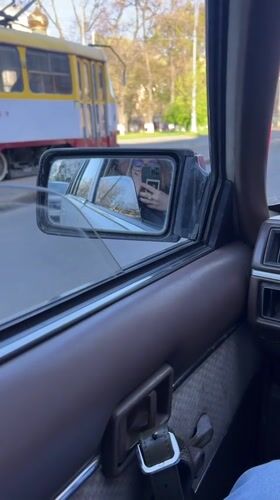 Woman takes selfie captured in car mirror reflection, Odesa