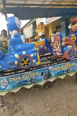 Cartoon kiddie train ride running in a Banyumas village setting