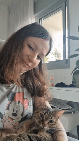 Woman pets tabby cat in morning moment in Ramat Gan
