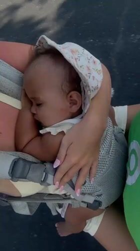 Baby napping in a carrier, wrapped in a floral blanket