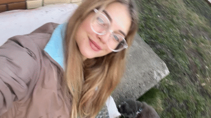 Woman films selfies with leashed cat in Russian village yard
