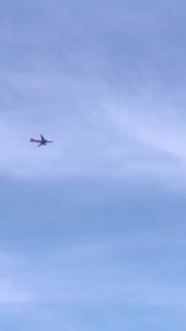 The video shows an airplane flying in the sky. The airplane is small and appears to be a passenger jet. The sky is blue with some clouds. The airplane is flying from left to right across the screen. The video is short and ends abruptly.
