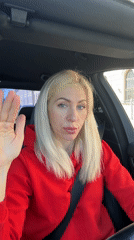 Woman in red hoodie drives past bridge with uniformed personnel