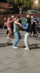 Nighttime dancing on a tiled plaza beside a mural wall