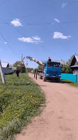 Utility truck with crane operates on rural road in Markovo