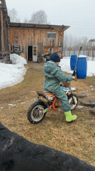 Child rides dirt bike in snowy Russian yard