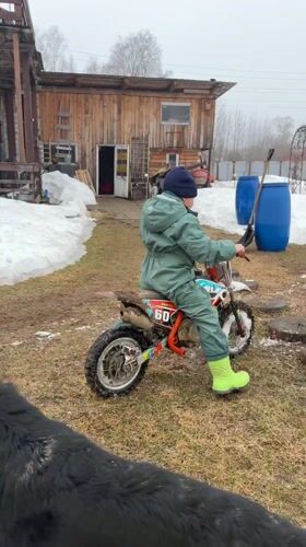 Child rides dirt bike in snowy Russian yard
