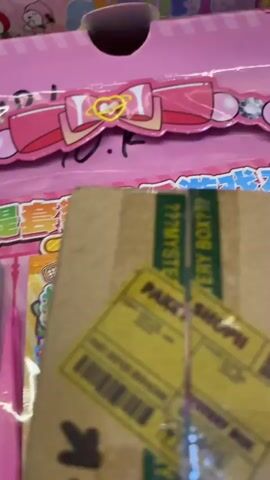 The video pans across a retail display of children's toys. The first object visible is a pink package with a bow and heart design, likely containing stickers or hair accessories. Next, a variety of colorful, spiky, ball-shaped toys with facial features are shown, some red and some green. Following this, several bubble blowers shaped like blue and yellow elephants are displayed in their packaging. The packaging of the bubble blowers is yellow and features the words "colorful fun" and "more bubble more fun." The overall environment appears to be a toy store aisle.
