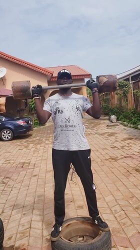 Person exercises with homemade weights on tire in Nigeria