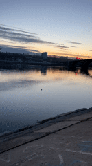 Woman playfully poses by river during golden hour in Irkutsk