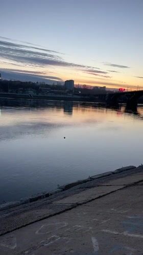 Woman playfully poses by river during golden hour in Irkutsk