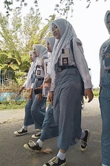 Students pass a roadside vendor on morning commute in Begajah