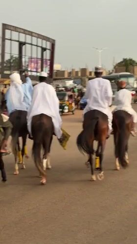 Riders in traditional dress move through Jos city streets