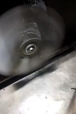 The video shows a close-up shot of a fan blade spinning rapidly, then the camera pans up to reveal the interior of what appears to be a refrigerator or freezer. The shelves are mostly empty, with a few containers and ice trays visible. The fan is located at the back of the appliance, likely responsible for circulating cold air. The lighting is dim, suggesting the appliance is either not in use or the interior light is off. The spinning fan creates a blur of motion, and the overall impression is one of a functional but currently inactive cooling unit.