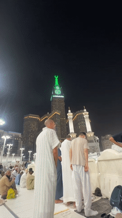 Abraj Al-Bait tower glowing green at night in Makkah