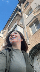 Woman in green walks, smiles in sunny Kryvyi Rih