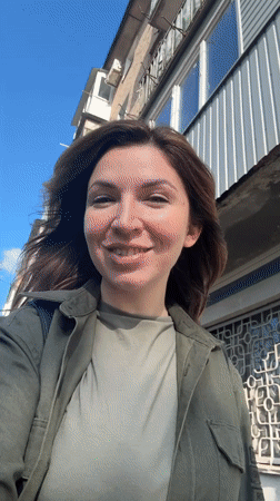 Woman in green walks, smiles in sunny Kryvyi Rih
