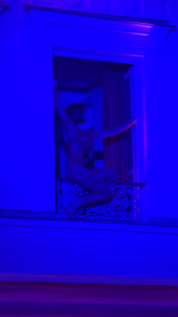 Woman dances on illuminated Parisian balcony Thursday evening
