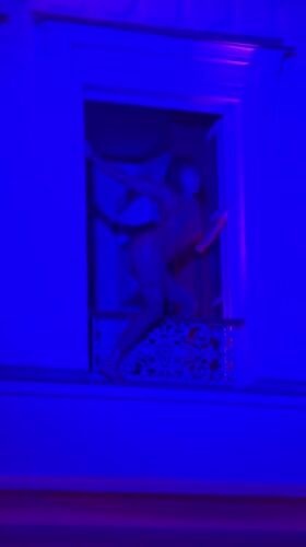 Woman dances on illuminated Parisian balcony Thursday evening