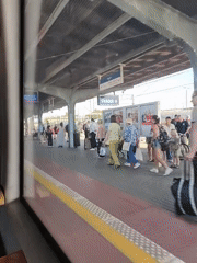Train departing Malbork station, passengers lingering on the platform.
