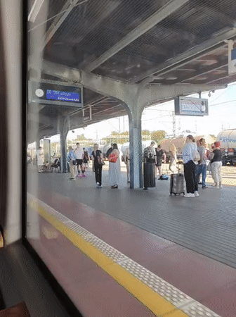 Train departing Malbork station, passengers lingering on the platform.