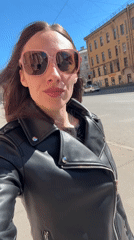 Woman waves to camera on sunny Saint Petersburg street