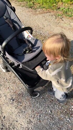 Toddler pushes stroller on gravel path in Erba