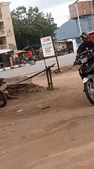 Motorcyclist rides dirt path in Adankolo, Nigeria street scene