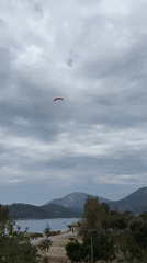 Paragliders soar over Fethiye's mountains under overcast skies