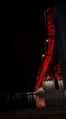 Krasnoyarsk bridge illuminated red at night, captured by witnesses