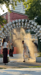Children play on scooters through misting archway in Moscow