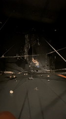 Aerial performer rehearses on suspended black structure in Paris theater