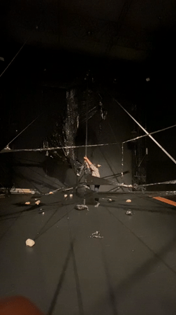 Aerial performer rehearses on suspended black structure in Paris theater