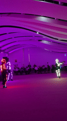 Illuminated costume dancers perform under purple lights in Iași