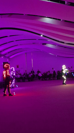 Illuminated costume dancers perform under purple lights in Iași