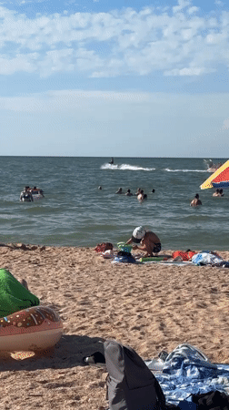 Crowded beach on a sunny day, swimming and sunbathing