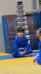 Kids' judo class in session, drills and rolls on the mat