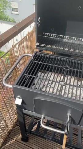 The video pans over a cutting board filled with several skewers of marinated meat and red onions, ready for grilling. The skewers are placed on a dark surface on what appears to be an outdoor balcony or deck. In the background, a blue swimming pool can be seen, along with a wooden railing adorned with string lights. A bamboo privacy screen is also visible. The lighting suggests it is daytime.