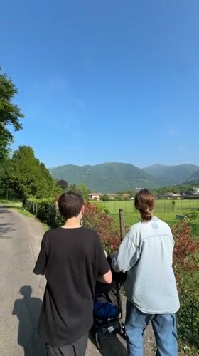 Family walks with stroller along mountain path in Erba