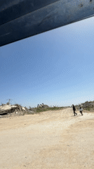 Vehicle travels through debris-scattered landscape under clear skies