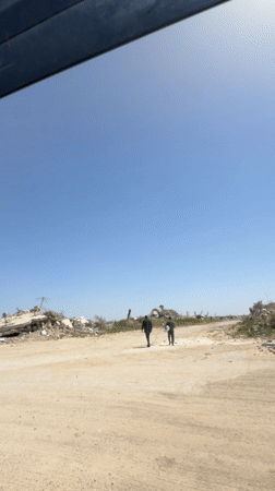 Vehicle travels through debris-scattered landscape under clear skies