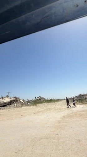 Vehicle travels through debris-scattered landscape under clear skies