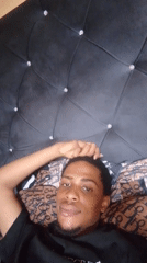Young man photographed smiling on bed with crystal headboard