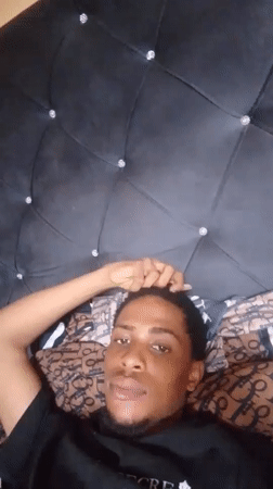 Young man photographed smiling on bed with crystal headboard