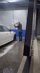 Man power-washes white sedan at Kazanlak car wash facility